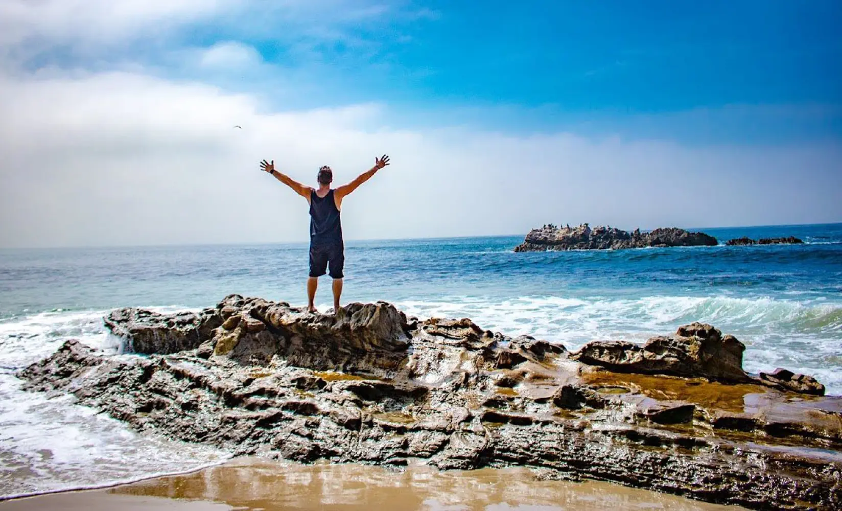 man at the beach with arms outstretched