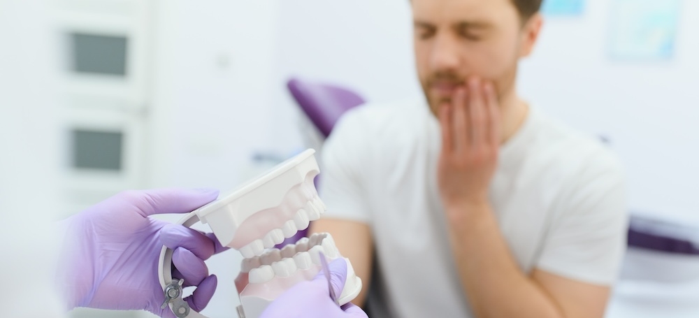 Young man in pain, looking upset at the dentist's office