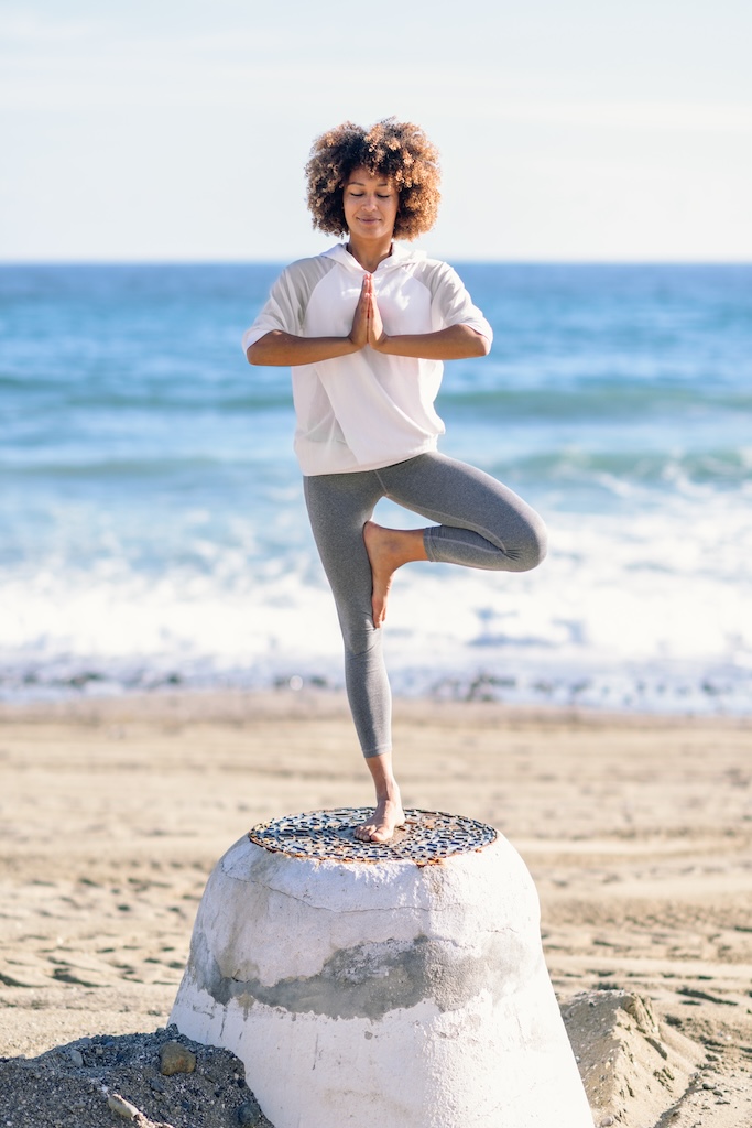 Young woman doing yoga in the beach at a Southern California rehab.